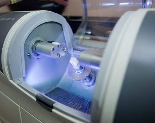 CEREC MC XL milling machine carving a custom porcelain crown in-office at Longmont Dental